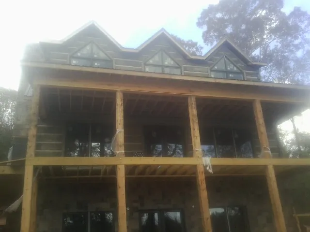 Dormers and porch framing on a large log home under construction — Roof Coating work by our crew in Lumberton